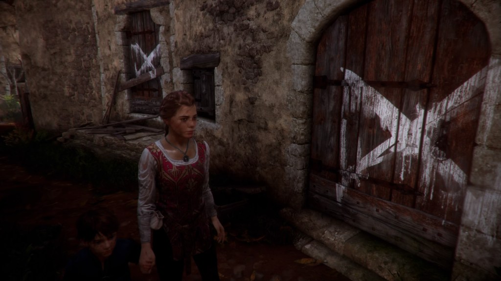 Amicia and Hugo stand next to a door with a big old white X on it