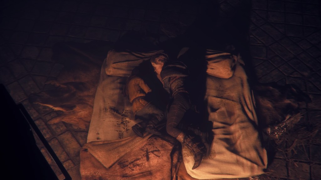 Amicia and Hugo lying down facing each other on their bedding. Hugo's head is obscured in shadow, making it unclear if he's actually looking at her. Amicia definitely is though.