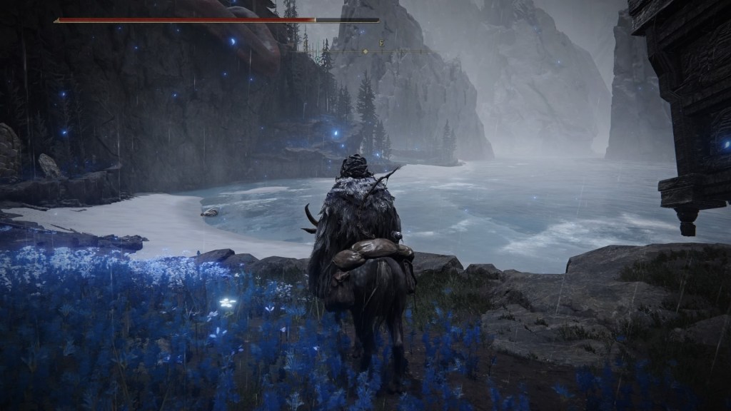 Part of the Cerulean Coast. On the left side there's a bunch of blue flowers that have a faint glow to them. Beyond that there's a misty looking beach and foggy cliffs in the distance. 