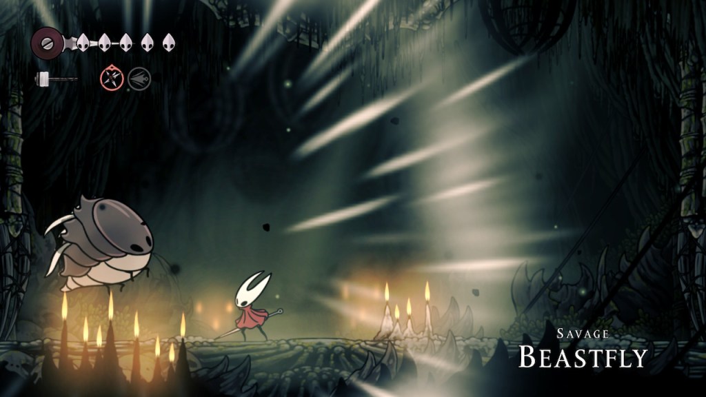 The Savage Beastfly, a big bulky warm dark gray creature with inexplicably functional small wings and black alien looking eyes. It roars, Hornet stands poised. The arena is the inside of a spooky Alien looking chapel that's dimly lit with some candles in the foreground and background.